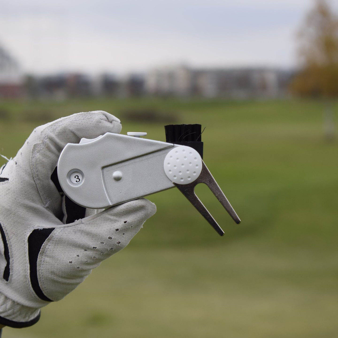 En närbild när en person med golfhandske håller i en 5 in 1 Club Cleaner.