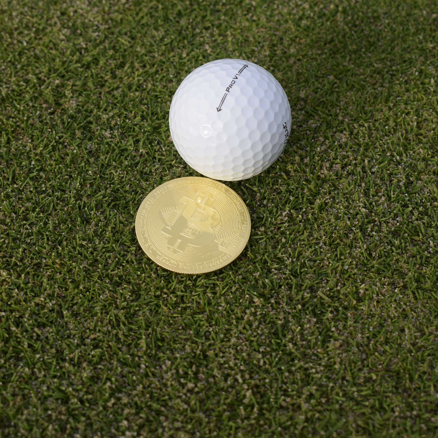 Närbild på en bitcoinballmarker som ligger på green bakom en boll