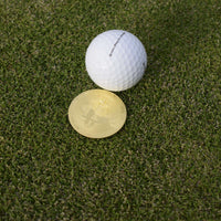 Närbild på en bitcoinballmarker som ligger på green bakom en boll