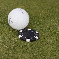 Närbild på den svarta markören som följer med när du köper Poker ballmarker som ligger på en greenn bakom en golfboll.