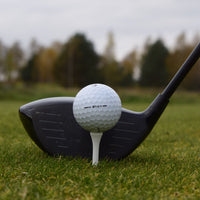 En närbild på en Taylormade Tp5 som ligger upp peggad framför en driver. 