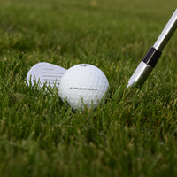 En närbild på en Taylormade Tour Response som ligger framför en golfklubba i ruffen.