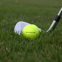 Närbild på Titleist Avx Gul 12-Pack framför en golfklubb som ligger i gräset.