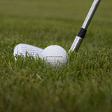 Närbild på Wilson FG Tour golfboll som ligger i gräset framför en golfklubba.