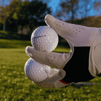 Kirkland Performance+ golfbollar som hålls av en golfare med golfhandske, hållbart och prisvärt val för golfare