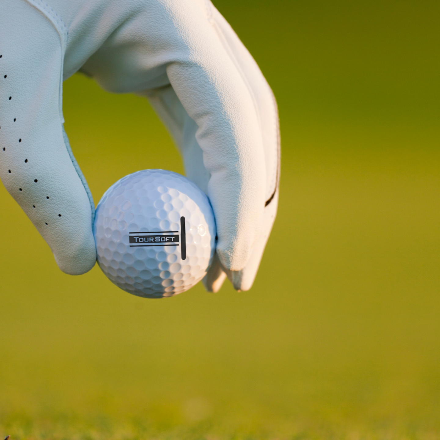 Titleist Tour Soft golfbollar 12-pack som hålls av en golfare med gräs som bakgrund